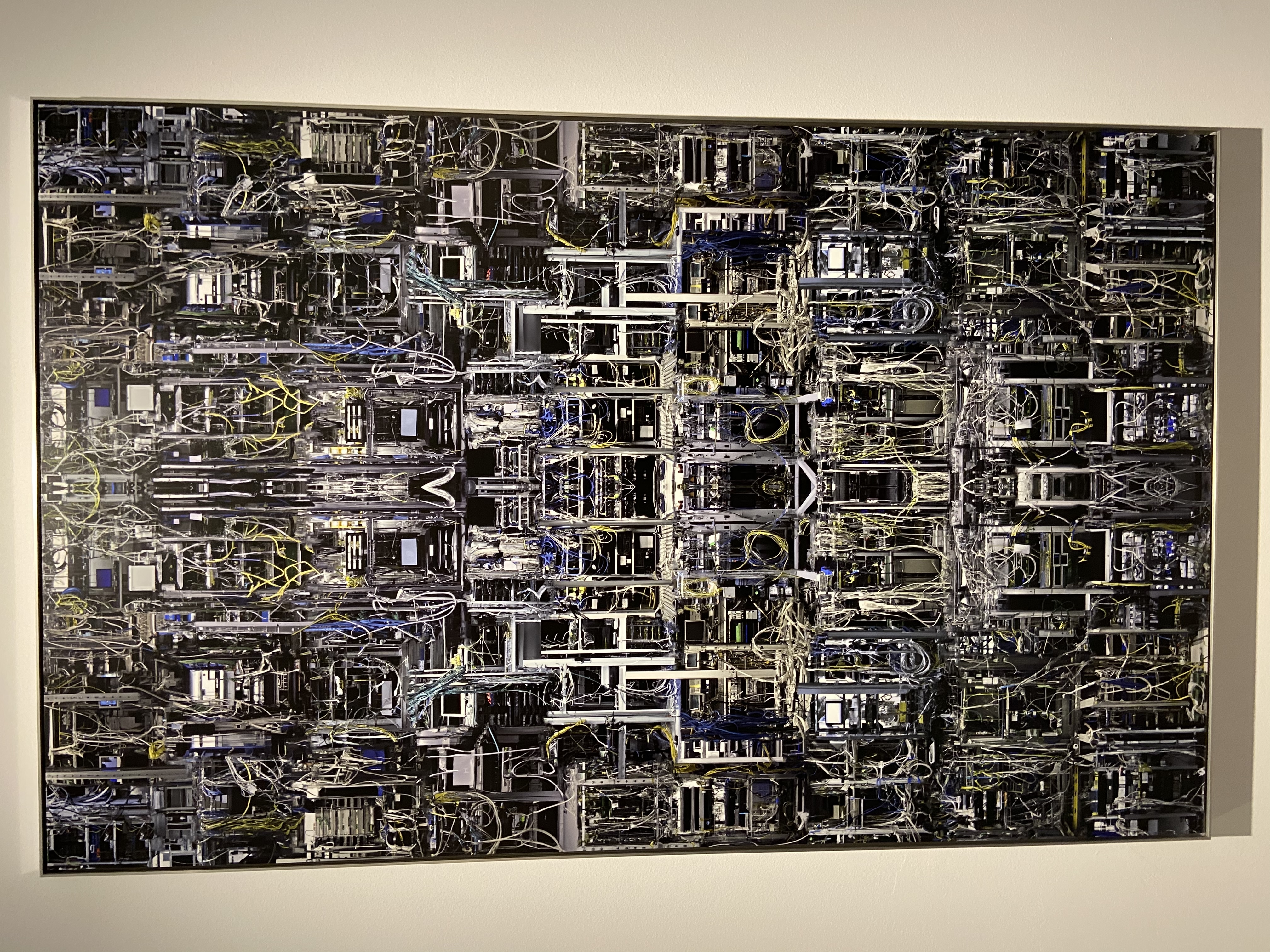 Un quadro che è formato da parti di computer, come fili, schede video, schede madre e processori, tutte unite fra loro creando una parte collegata e intersecata. i fili creano una sensazione di disordine, sono tutti intrecciati fra loro